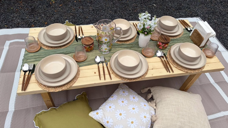 Picnic setup close-up with styled tableware and floral accents